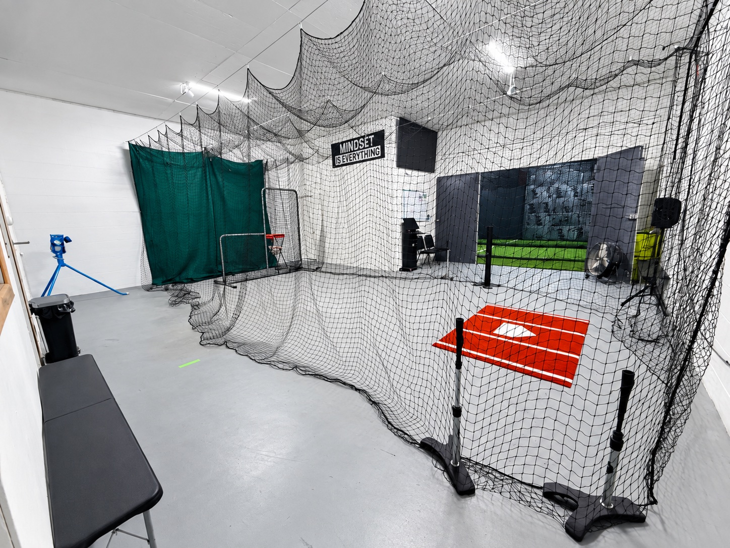 Trackside’s HitTrax room with netted hitting area, red hitting mat, and viewing space
